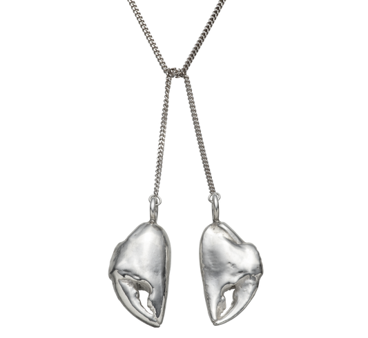 A close up shot of a sterling silver lariat necklace made from casts of crab claws by Violette Stehli