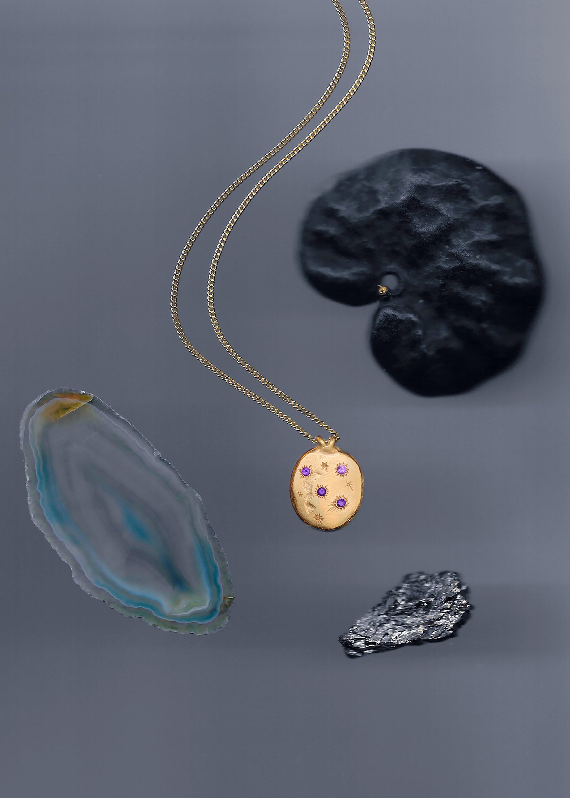 A precious but rough 18-karat gold medallion set with four amethysts and celestial engravings. Hand sculpted by Violette Stehli.