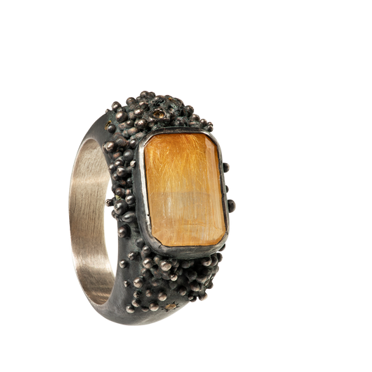 A massif sterling silver ring with a beautiful emerald-cut rutilated quartz and six yellow sapphires. The ring is hand sculpted and cast in sterling silver with a deep black patina.