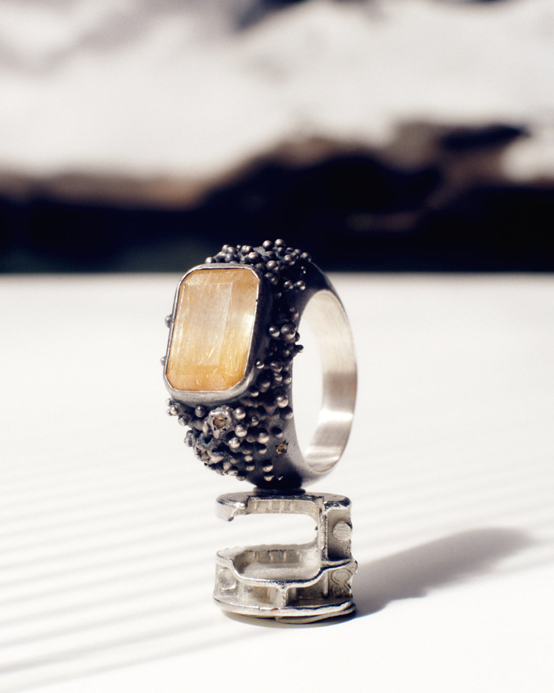 A massif sterling silver ring with a beautiful emerald-cut rutilated quartz and six yellow sapphires. The ring is hand sculpted and cast in sterling silver with a deep black patina. Made by Violette Stehli. Photo by Daniel Antropik.