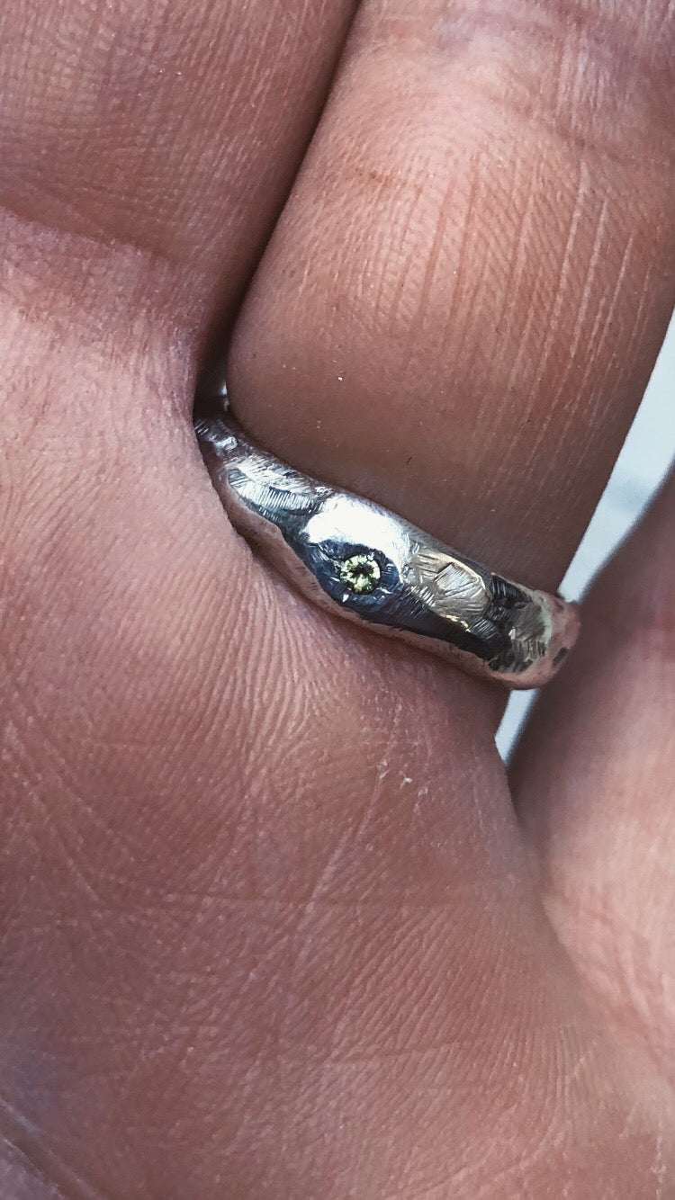 A fluid and textured sterling silver band set with a green sapphire. Made by Violette Stehli.