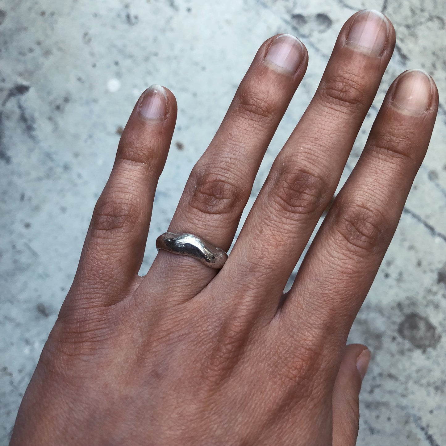 A fluid and textured sterling silver band set with a green sapphire. Made by Violette Stehli.
