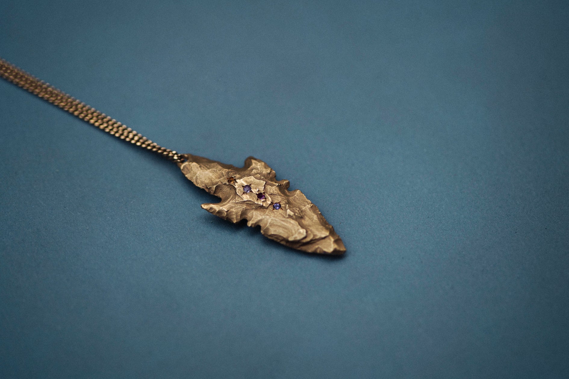 A pendant made from the cast of a neolithic era arrowhead. It is set with ruby, amethyst, pink and yellow sapphires on a curb-link chain. Handmade by Violette Stehli. Photo Cécile Chabert.