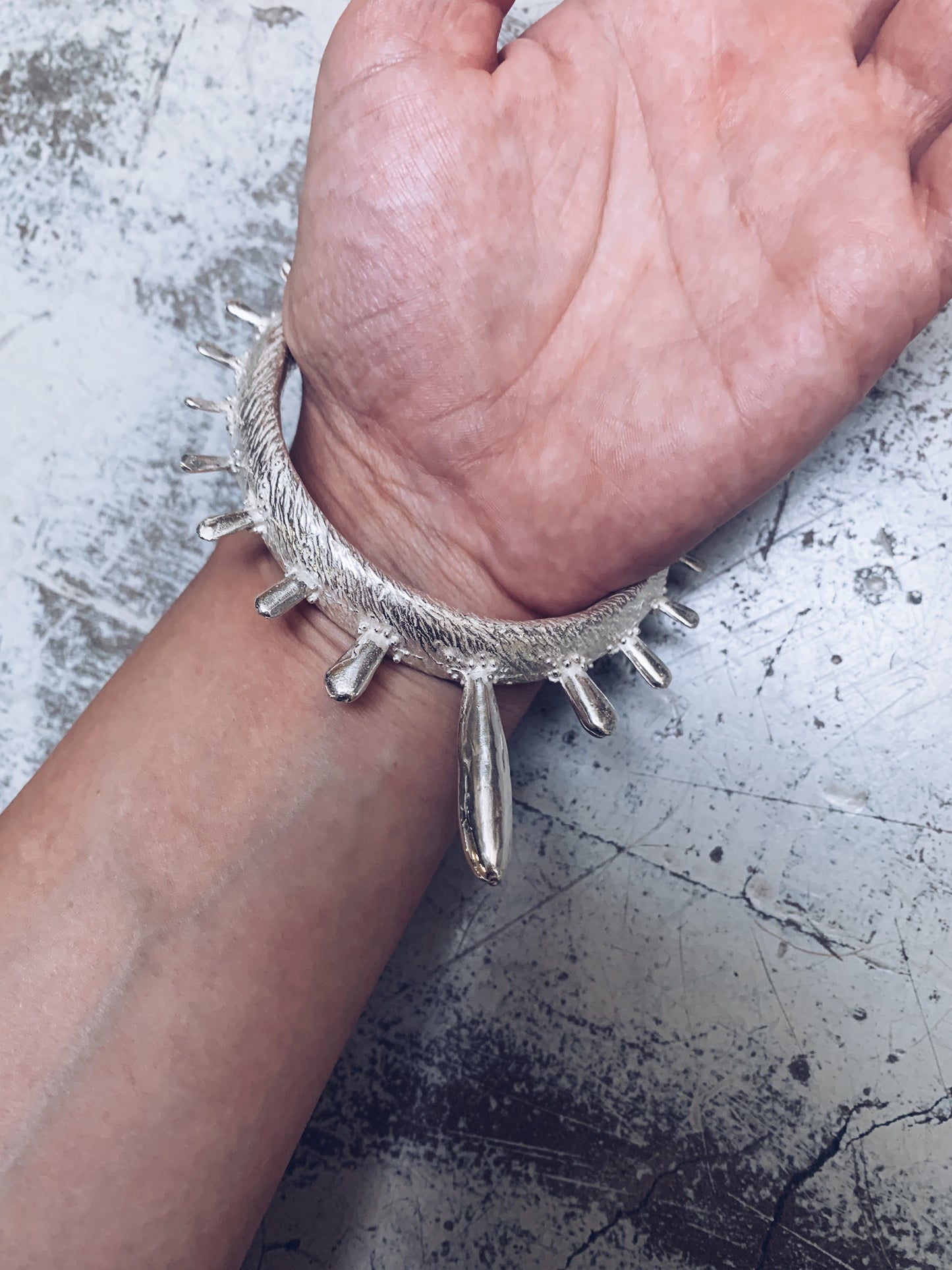 A colossal sterling silver bangle adorned with sea urchin spines and delicate granulation details evoking ancient Etruscan jewelry. Made by Violette Stehli