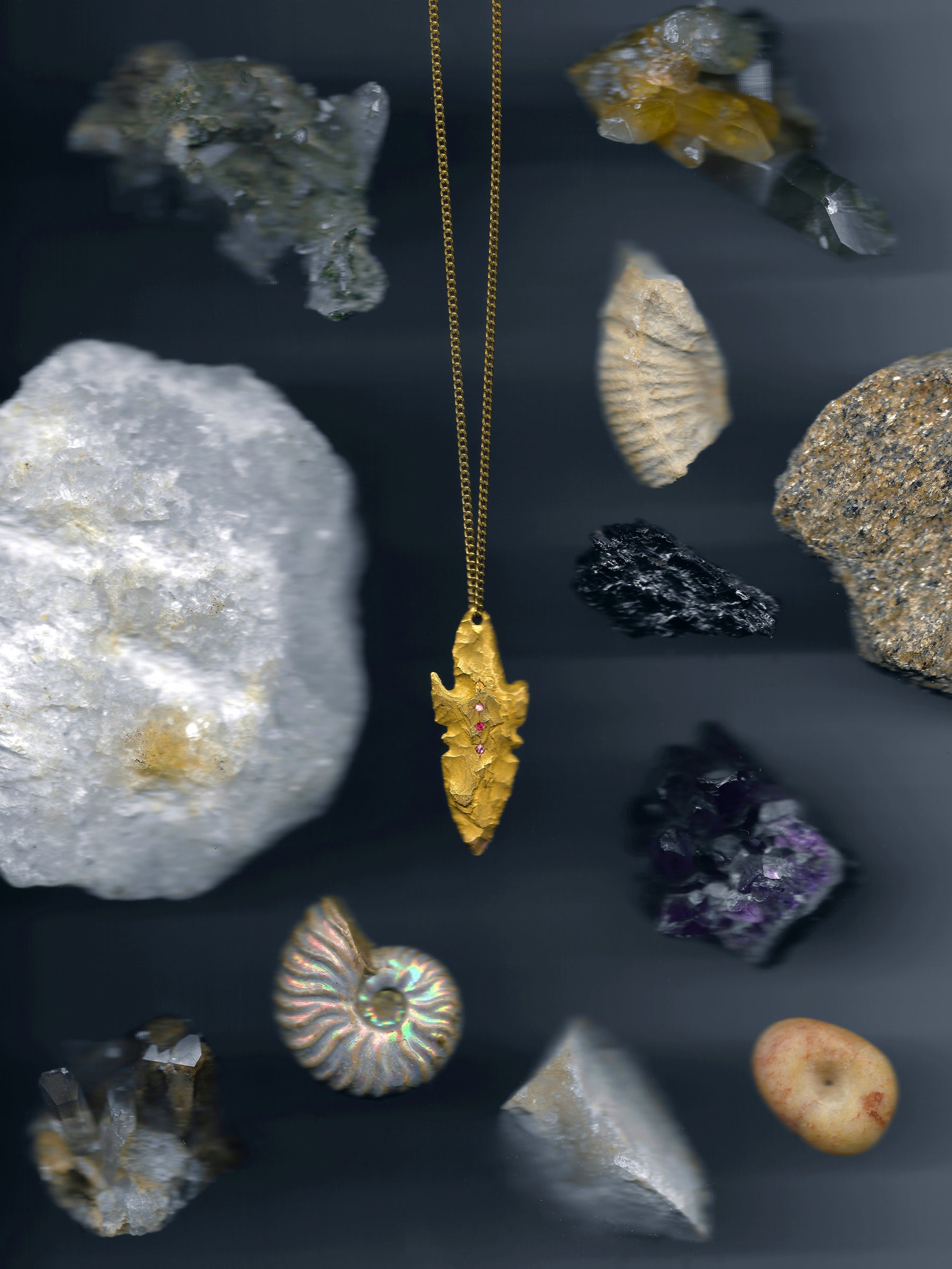A pendant made from the cast of a neolithic era arrowhead. It is set with ruby, amethyst, pink and yellow sapphires on a curb-link chain. Handmade by Violette Stehli.