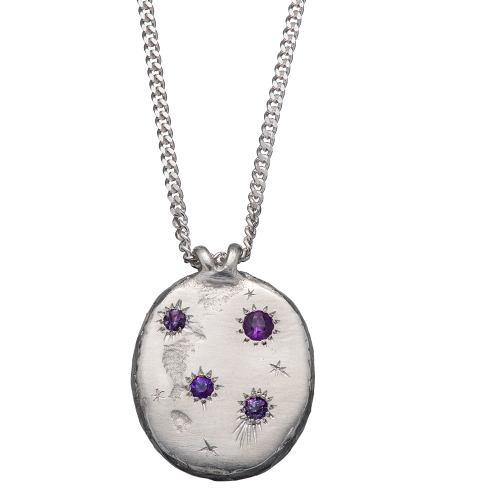 A precious but rough sterling silver medallion set with four precious stones and celestial engravings.