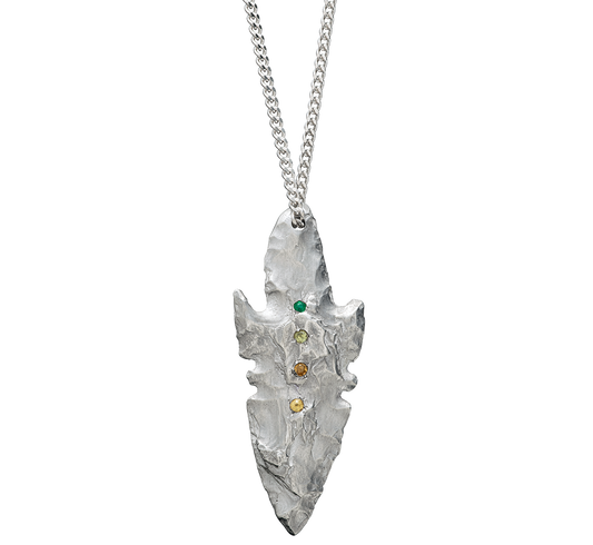 A pendant made from the cast of a neolithic era arrowhead. It is set with emerald, green and yellow sapphire and citrine on a curb-link chain. Handmade by Violette Stehli
