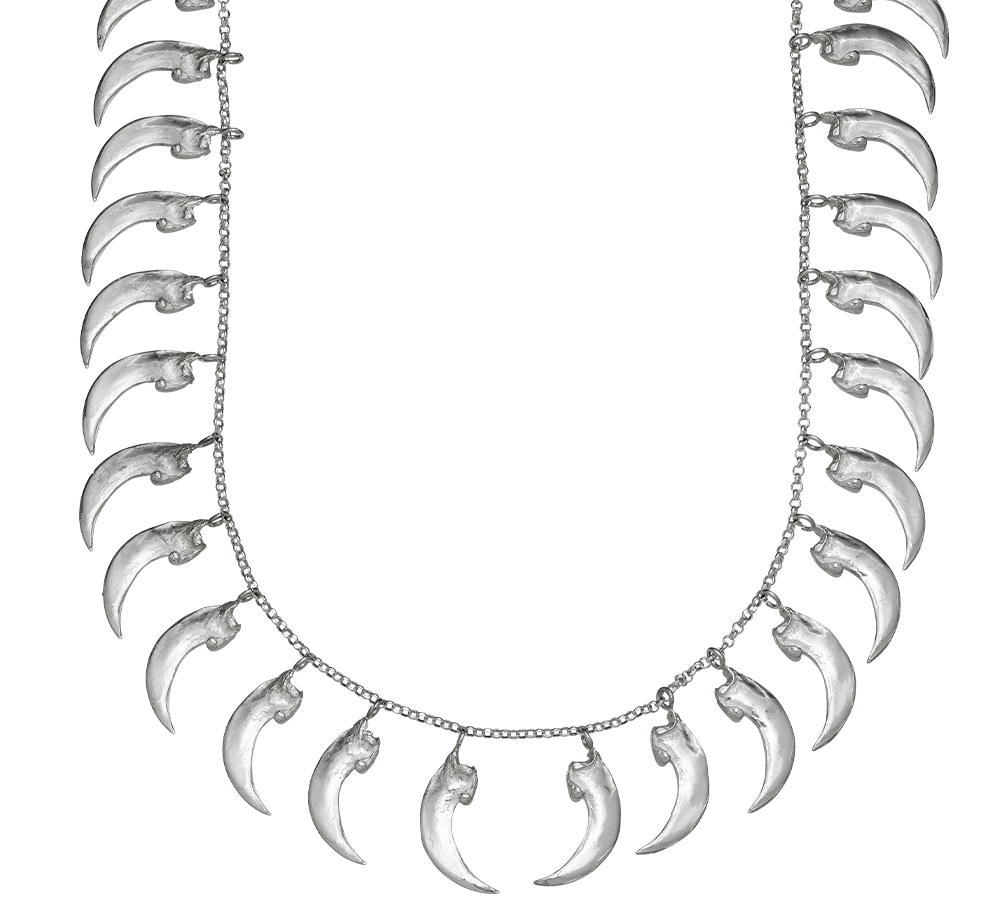A close-up of a sterling silver necklace made from cast replicas of bat claws. The claws hang from a rolo link chain. The necklace is tough but delicate, like armor. Handmade by Violette Stehli