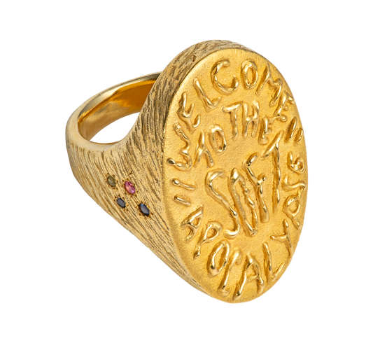 A massive gold vermeil ring made by Violette Stehli. Set with sapphires and peridot and embossed with handwritten text that reads "welcome to the soft apocalypse".