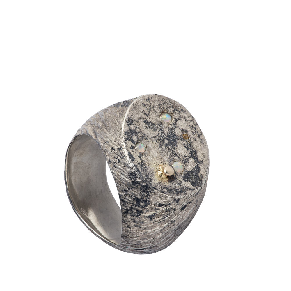 A massive distressed sterling silver and 18-karat gold signet set with opals and sapphires. The ring looks like the surface of the moon annd is hand-sculpted by Violette Stehli.