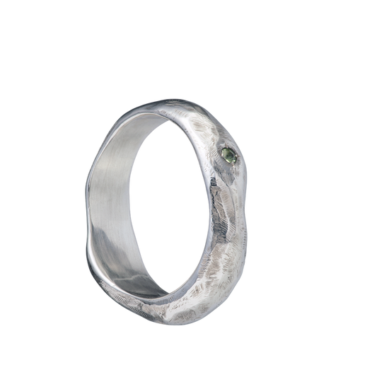 A fluid and textured sterling silver band set with a green sapphire. Made by Violette Stehli.