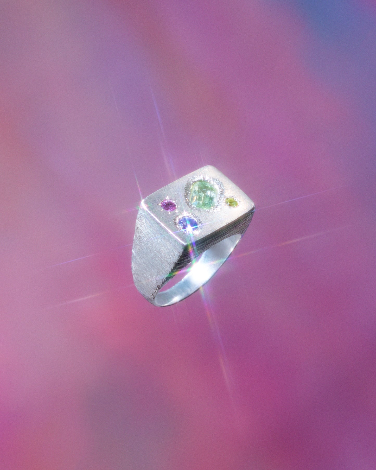 A rough but precious rectangular signet in sterling silver set with a mint-green tourmaline, a peridot, a tanzanite and a rhodolite garnet. Hand sculpted by Violette Stehli. Photo by Julia Grandperret Motin.