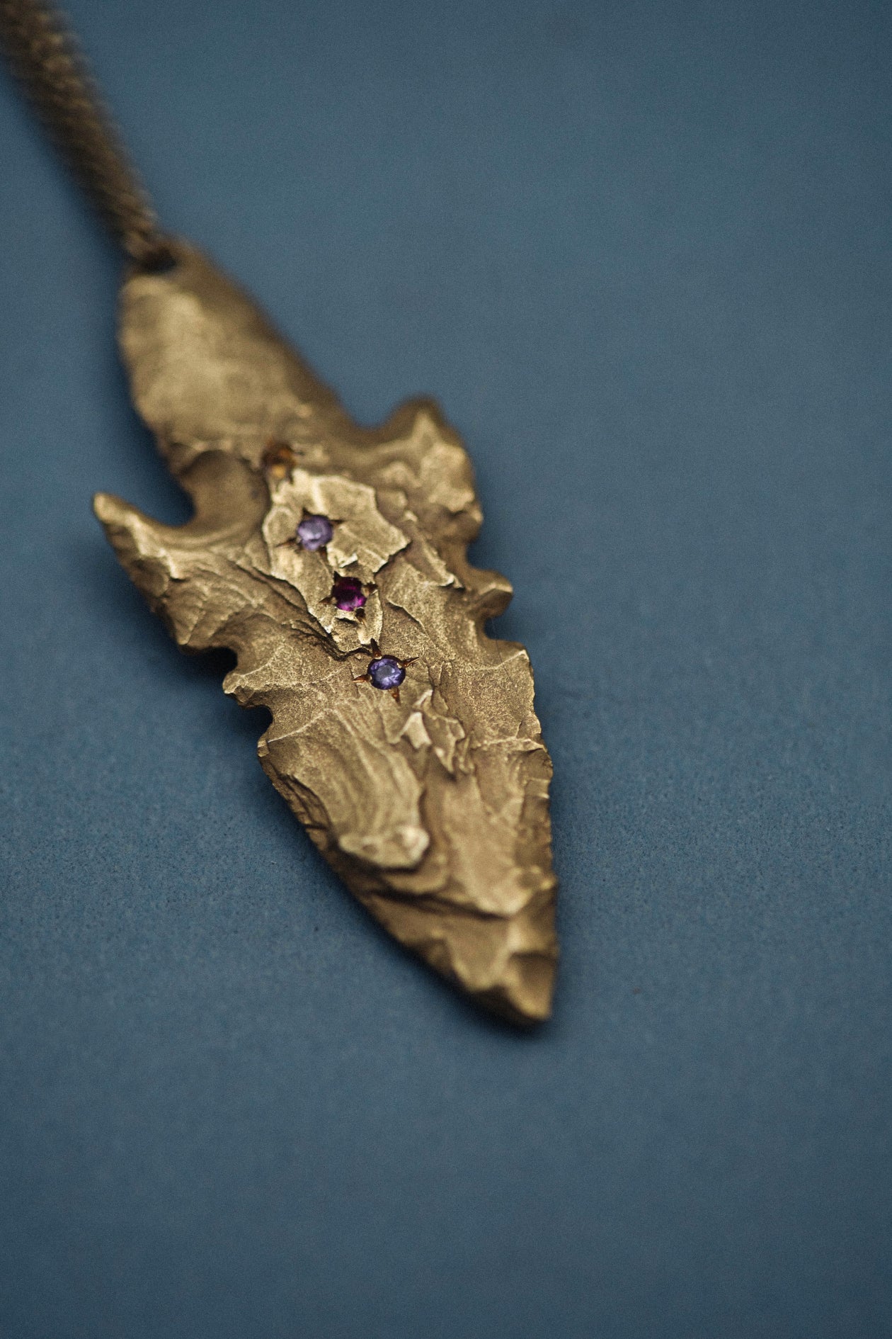 A pendant made from the cast of a neolithic era arrowhead. It is set with ruby, amethyst, pink and yellow sapphires on a curb-link chain. Handmade by Violette Stehli. Photo Cécile Chabert.