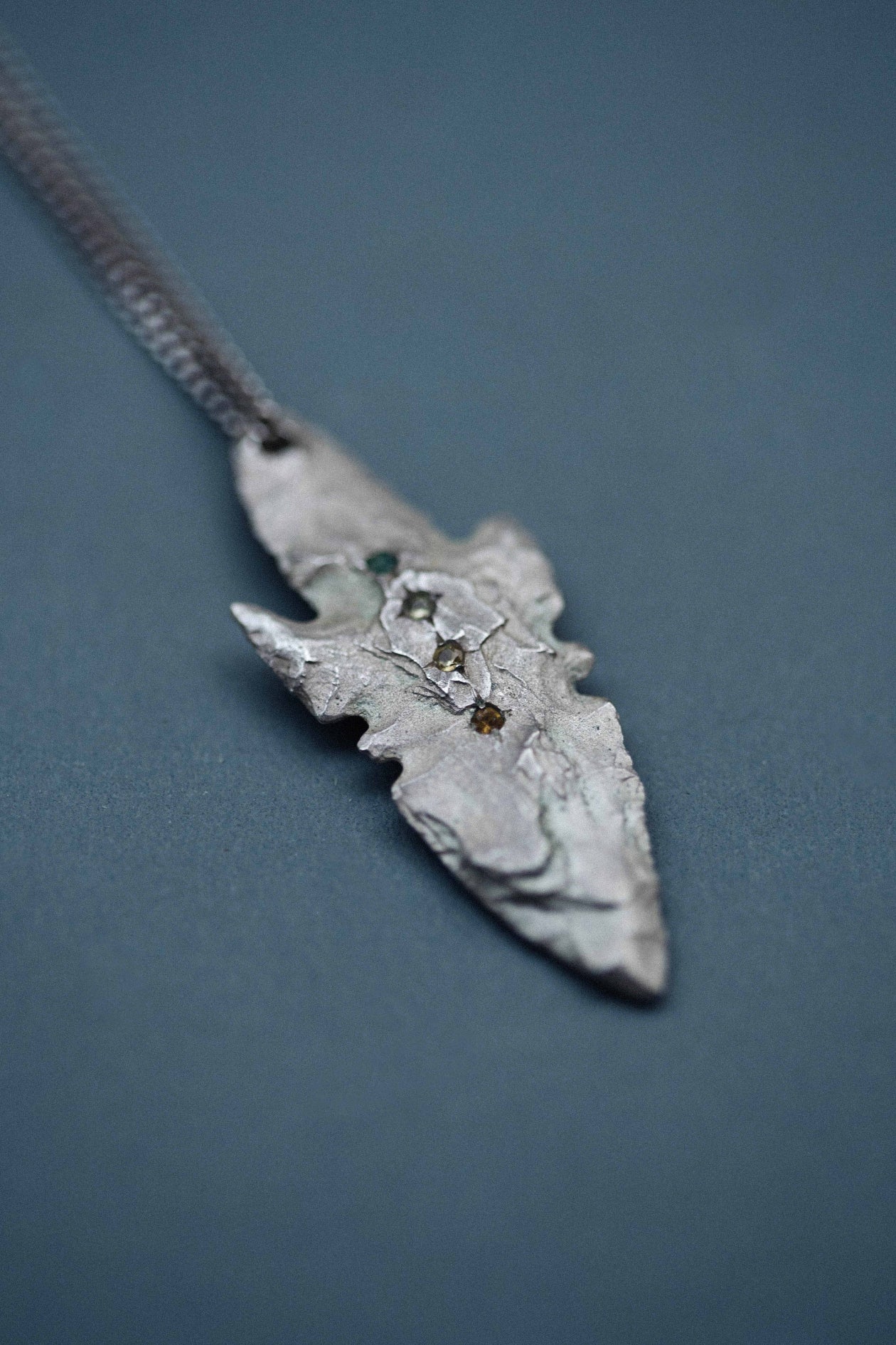 A pendant made from the cast of a neolithic era arrowhead. It is set with emerald, green and yellow sapphire and citrine on a curb-link chain. Handmade by Violette Stehli. Photo Cécile Chabert.