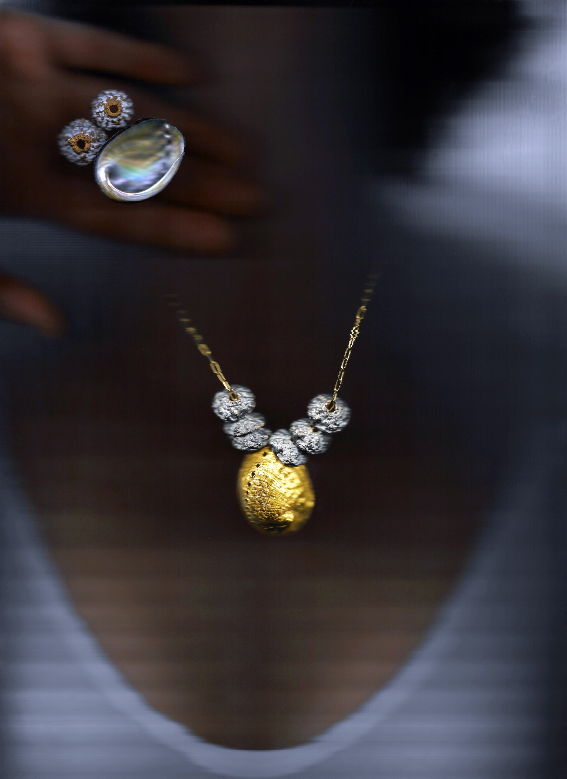 A sterling silver and gold vermeil necklace made from casts of eucalyptus seed caps and an abalone shell. Made by Violette Stehli.