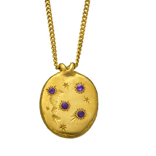 A precious but rough 18-karat gold medallion set with four amethysts and celestial engravings.