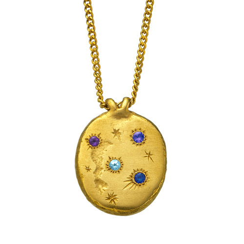 A precious but rough gold vermeil medallion set with four precious gems and celestial engravings.