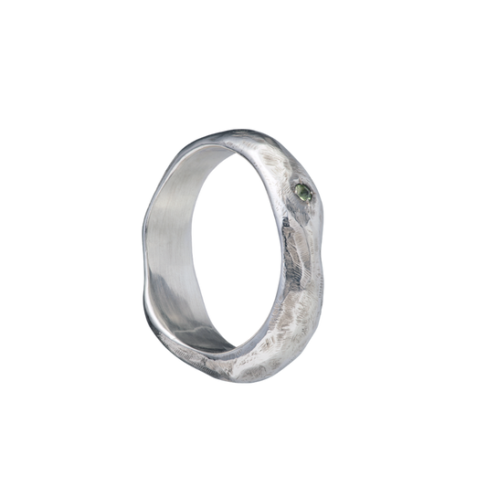 A fluid and textured sterling silver band set with a green sapphire. Made by Violette Stehli.