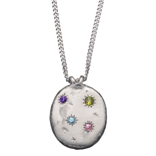 A precious but rough sterling silver medallion set with four precious stones and celestial engravings.