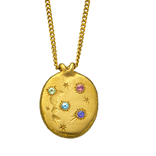 A precious but rough 18-karat gold medallion set with four precious gems and celestial engravings.