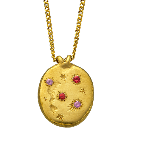 A precious but rough gold vermeil medallion set with four precious gems and celestial engravings.